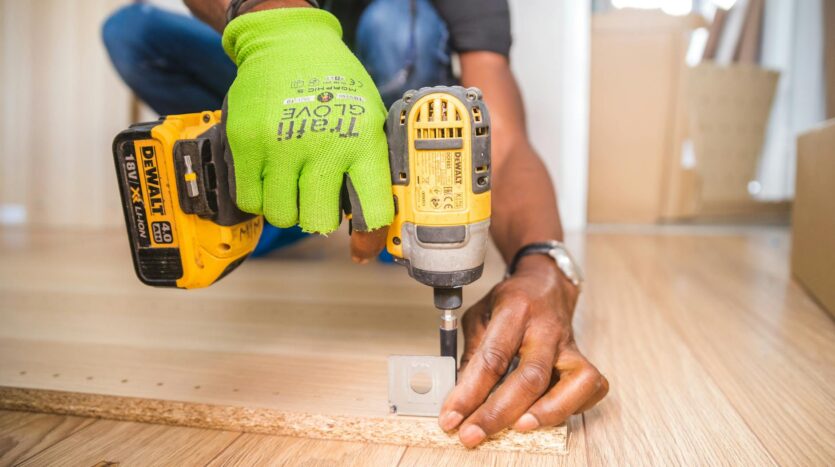 person using dewalt cordless impact driver on brown board